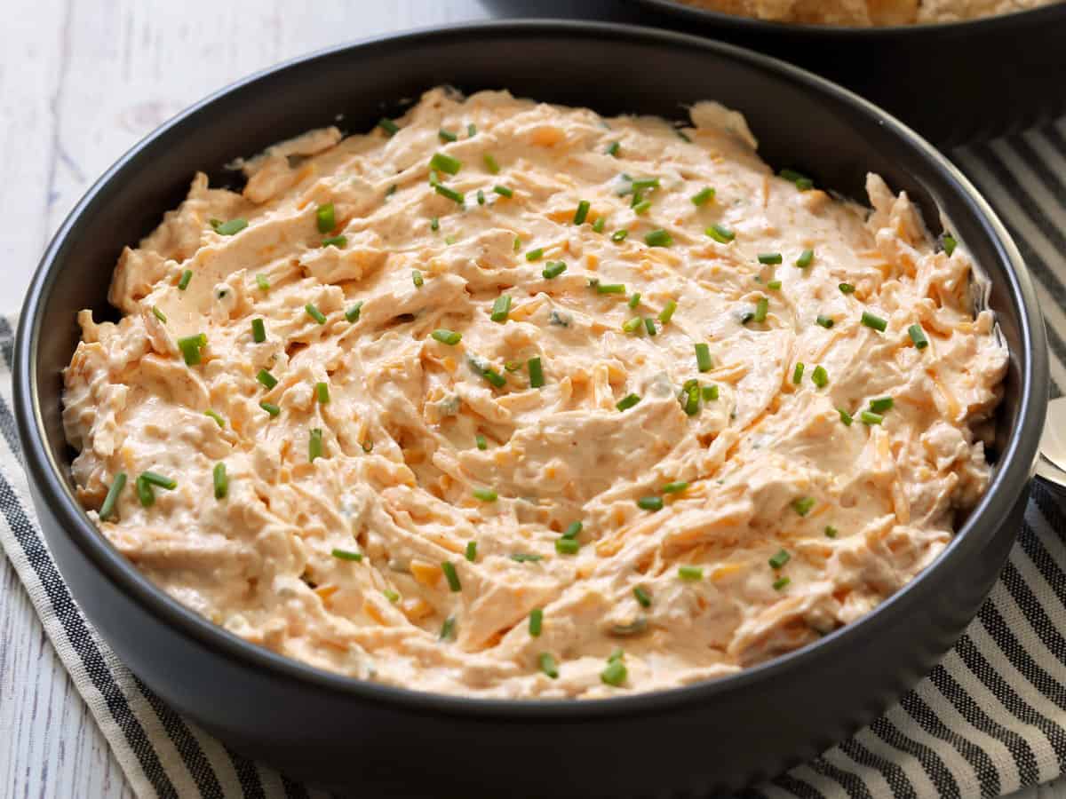 Cream cheese dip is served in a dark bowl.