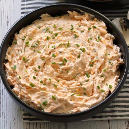 Cream cheese dip is served in a dark bowl.