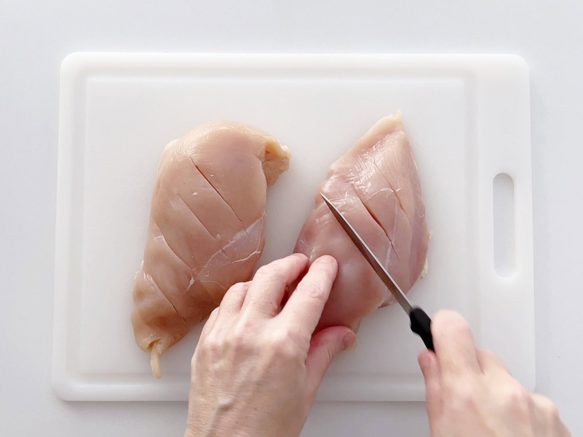 Cutting slits in the chicken.