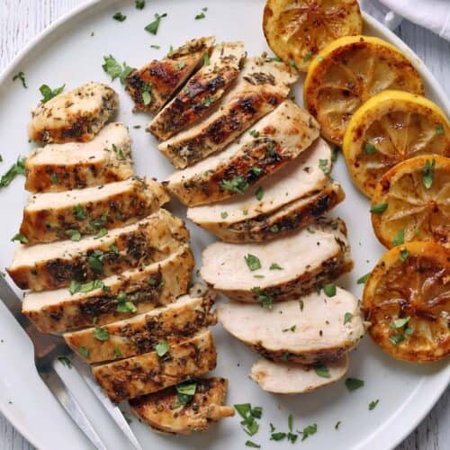 Greek chicken with lemons is served on a white plate.