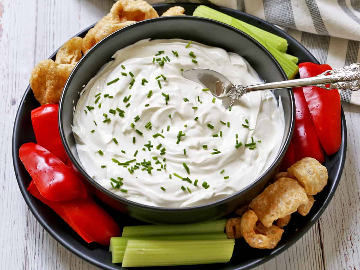 Greek yogurt dip is served with veggies and pork rinds.