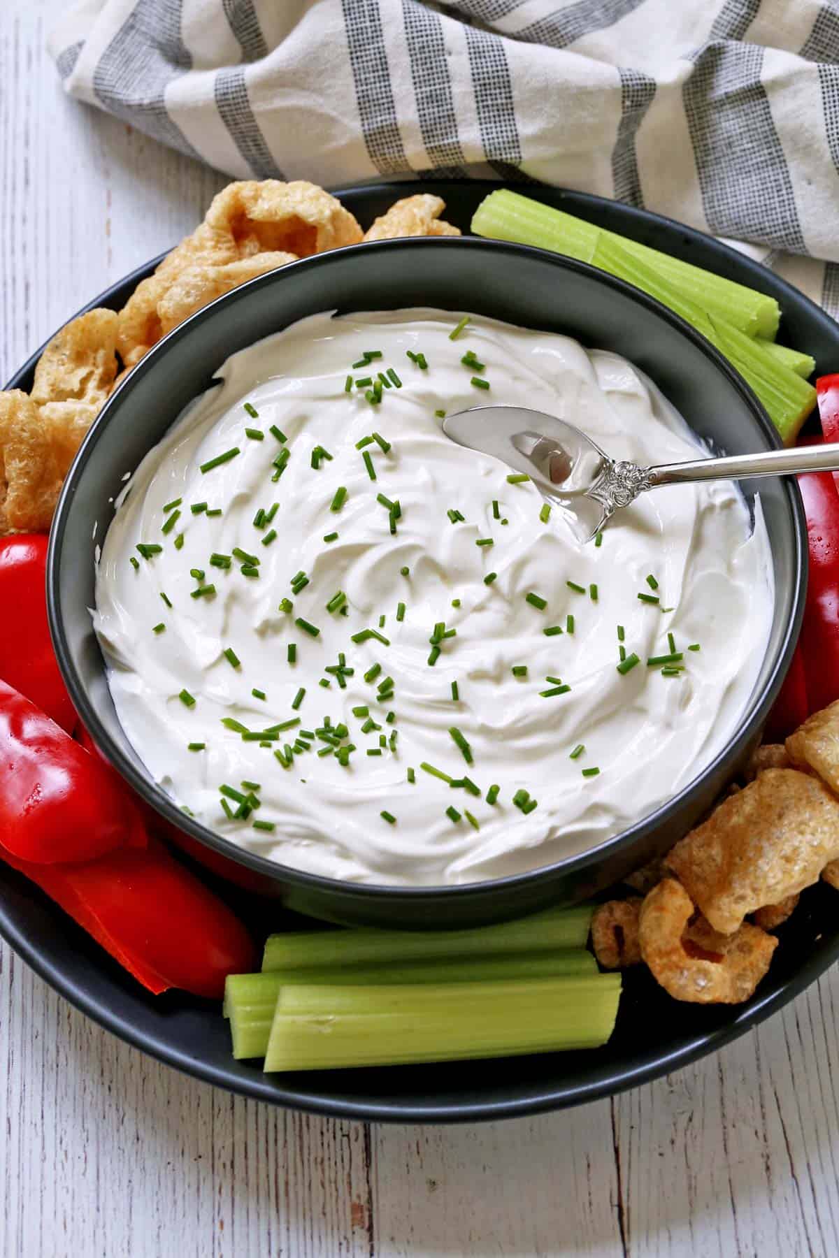 Greek yogurt dip is served with veggies and pork rinds.