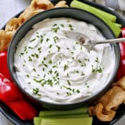 Greek yogurt dip is topped with chives and served with veggies and pork rinds.