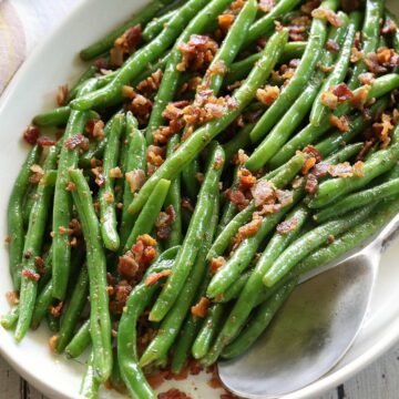 Green beans with bacon served with a serving spoon.