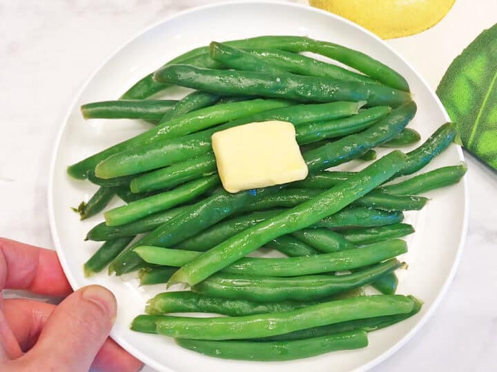 The green beans are served, topped with butter.