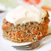 A slice of keto carrot cake is served on a white plate with a fork.