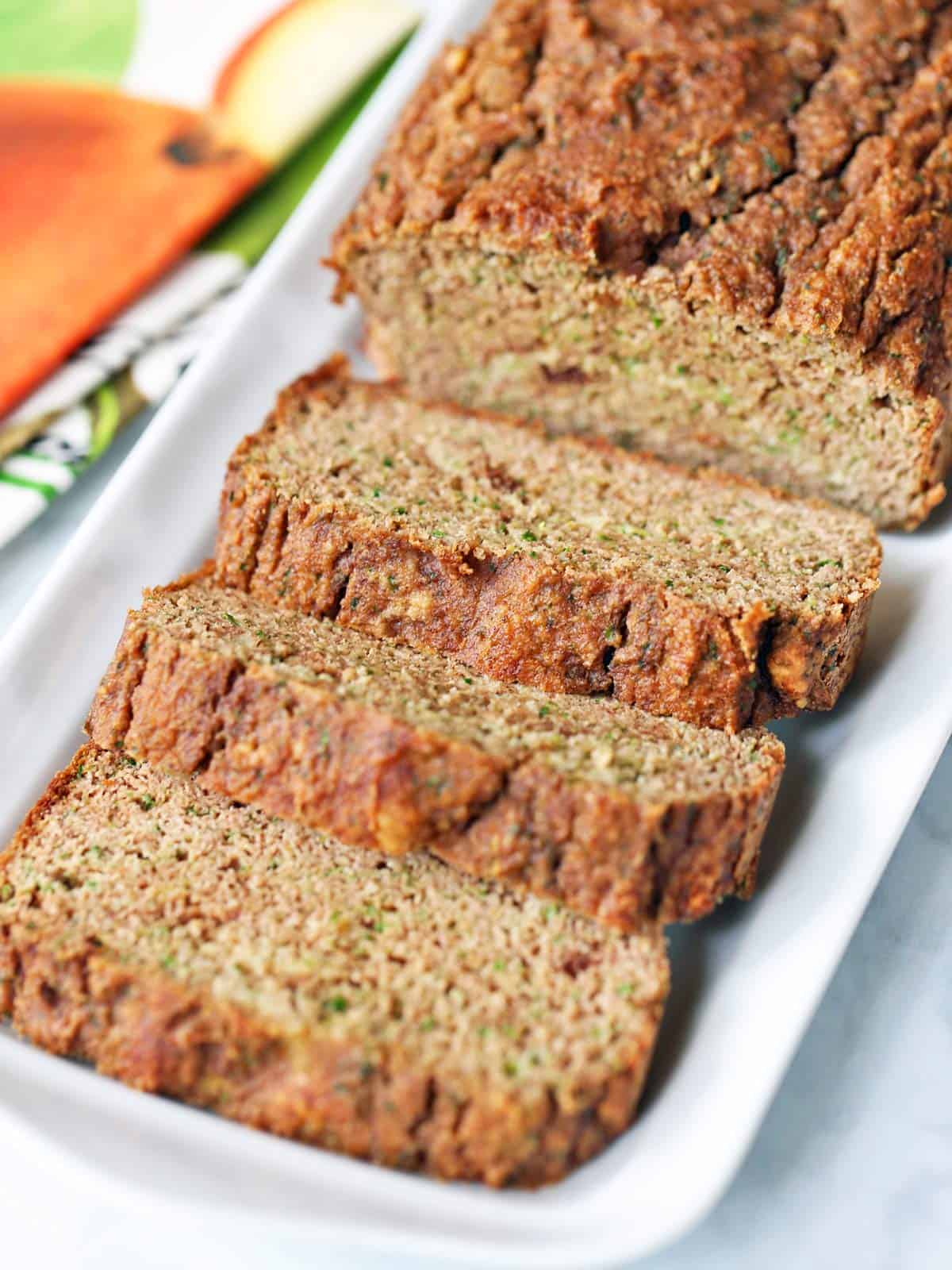 Sliced keto zucchini bread is served on a white serving tray.