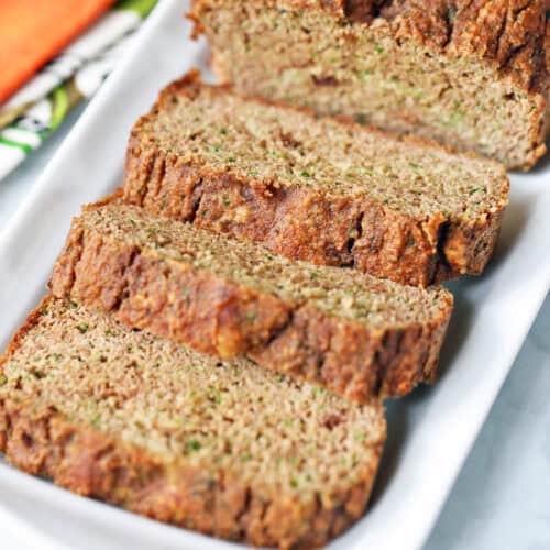 Sliced keto zucchini bread is served on a white serving tray.