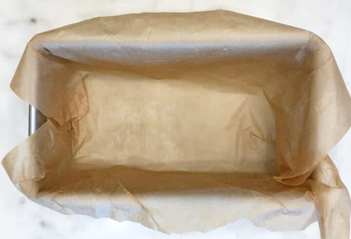 A loaf pan is lined with parchment paper.
