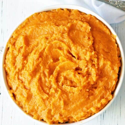 Mashed sweet potatoes are served in a bowl.