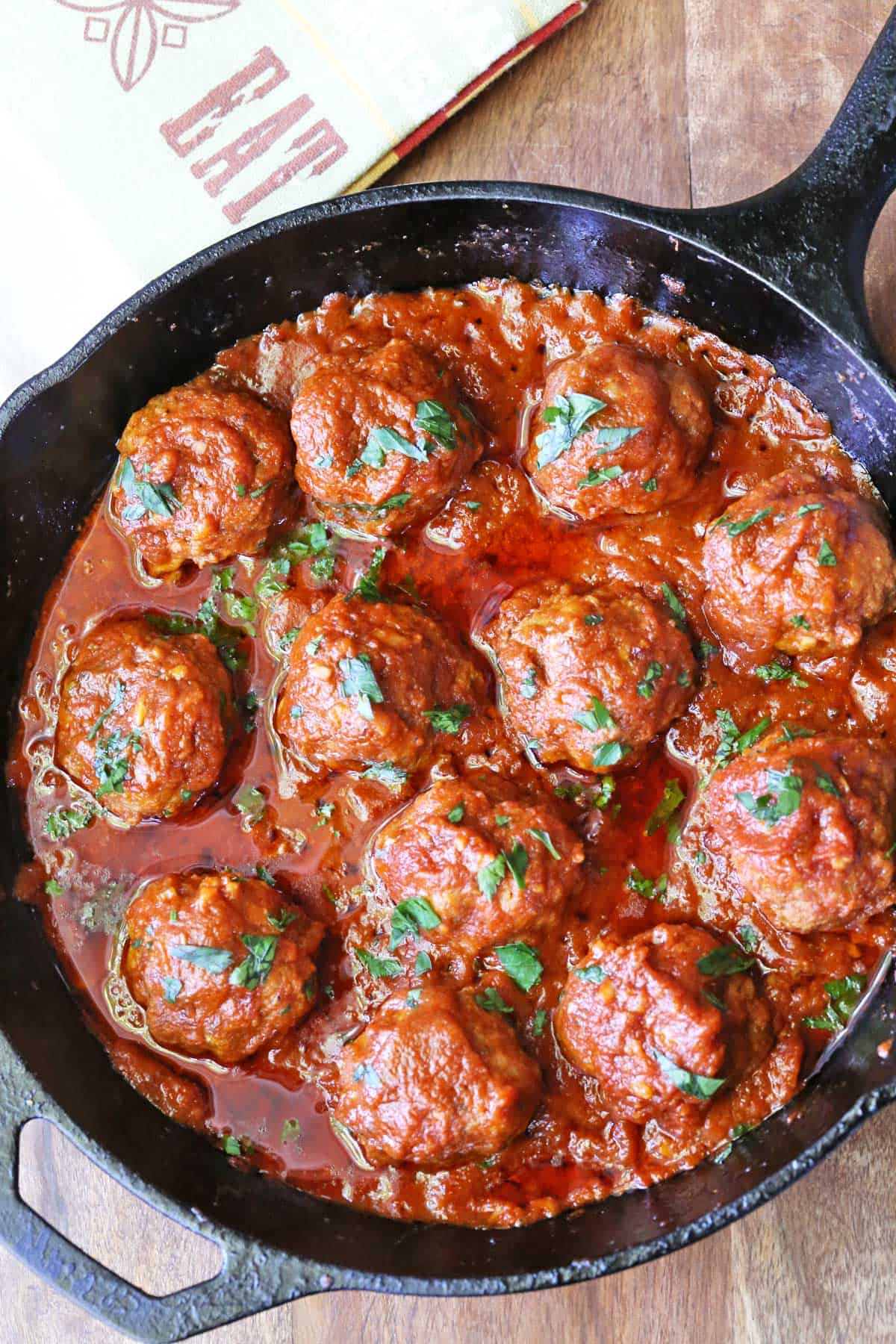 Meatballs in tomato sauce are served in a cast-iron skillet.