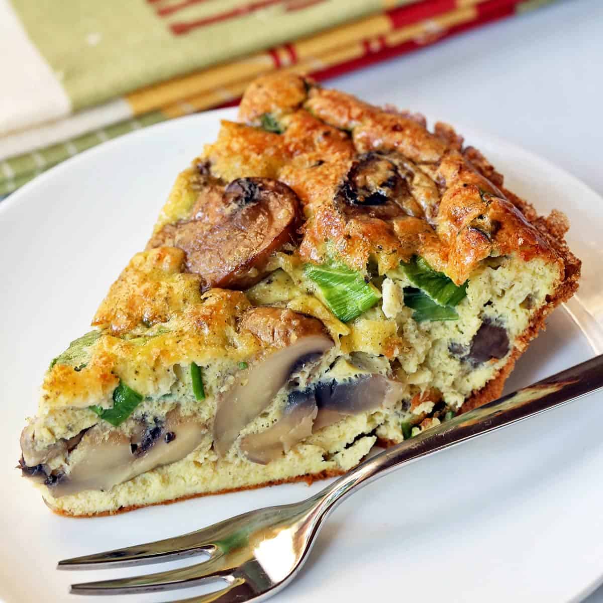 A slice of mushroom frittata is served with a fork.