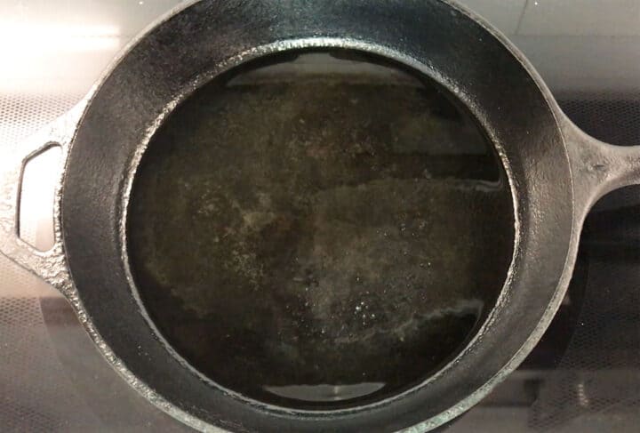 Heating oil in a cast-iron skillet.