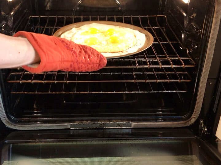 Placing the pizza back in the oven.