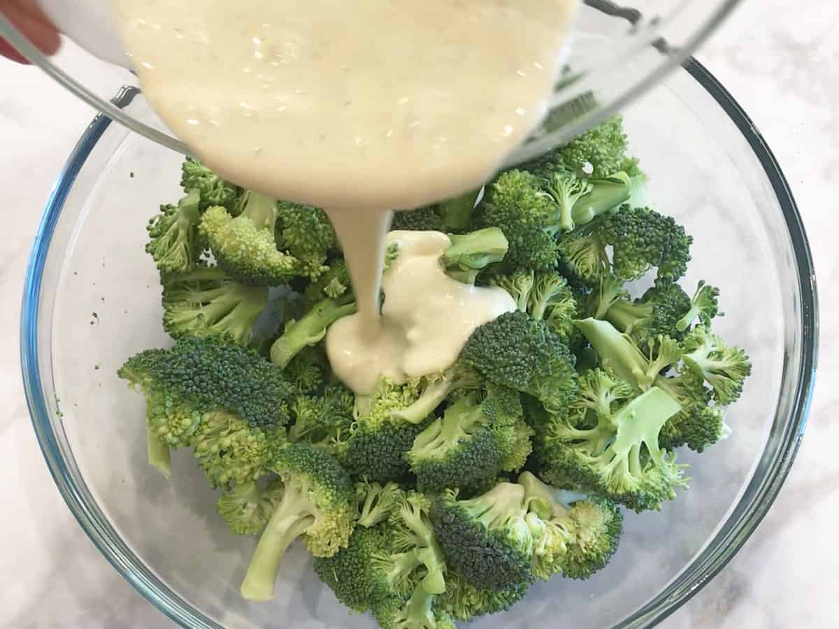 Pouring the dressing on the broccoli.