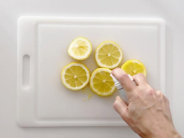 Spraying lemon slices with olive oil.