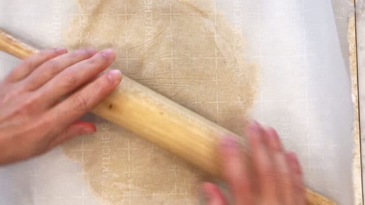 Flattening the dough with a rolling pin.