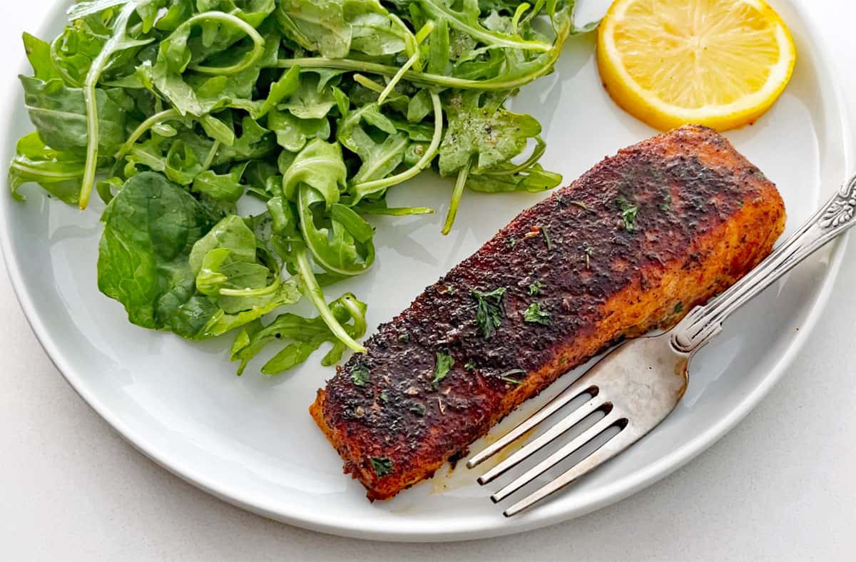 The salmon is served with arugula salad.
