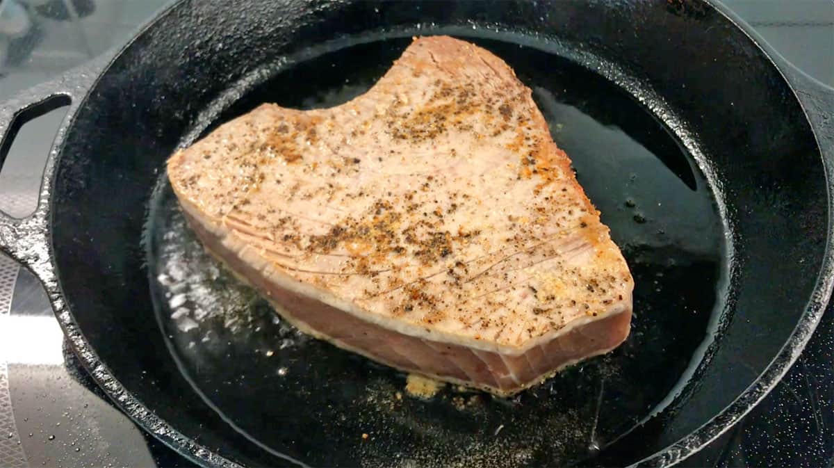 Searing the tuna steak in a skillet.