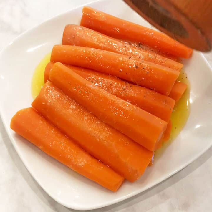 Seasoning the carrots with freshly ground black pepper.