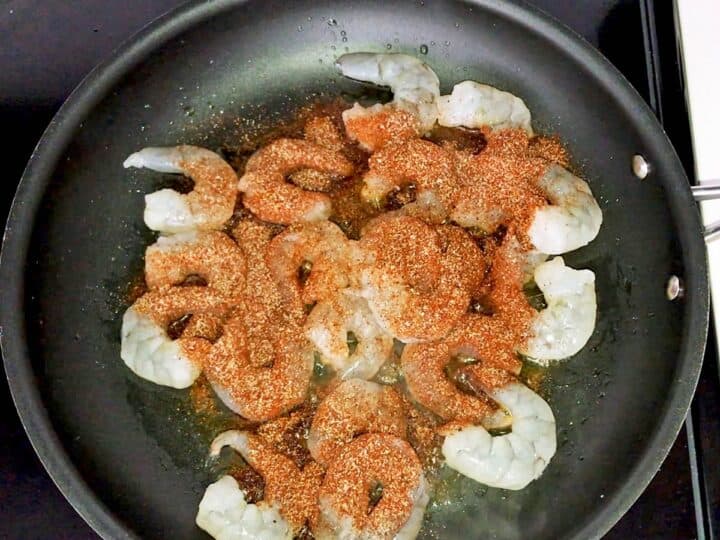 Raw shrimp and spices in a skillet.