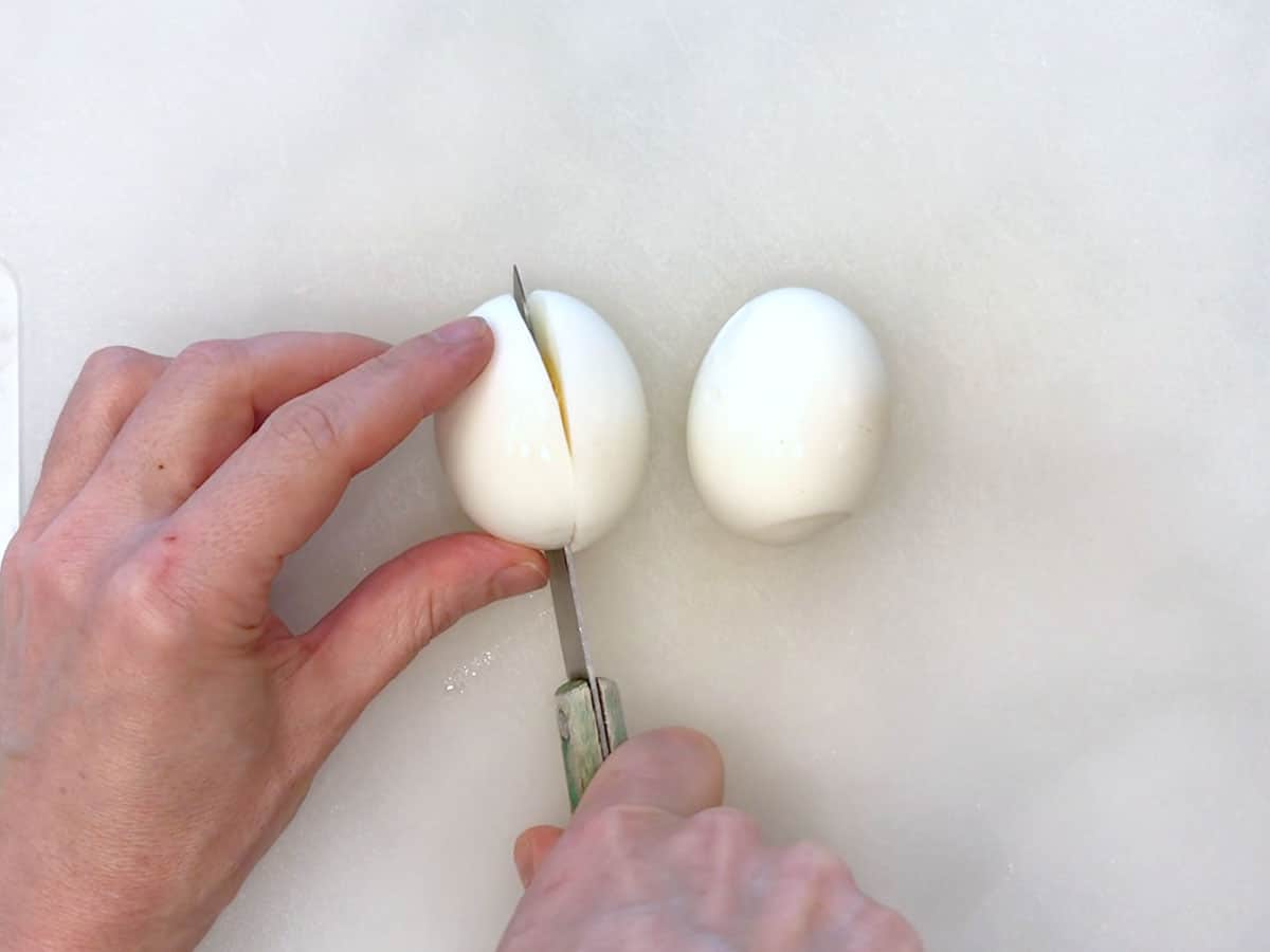 Slicing an egg on a cutting board.
