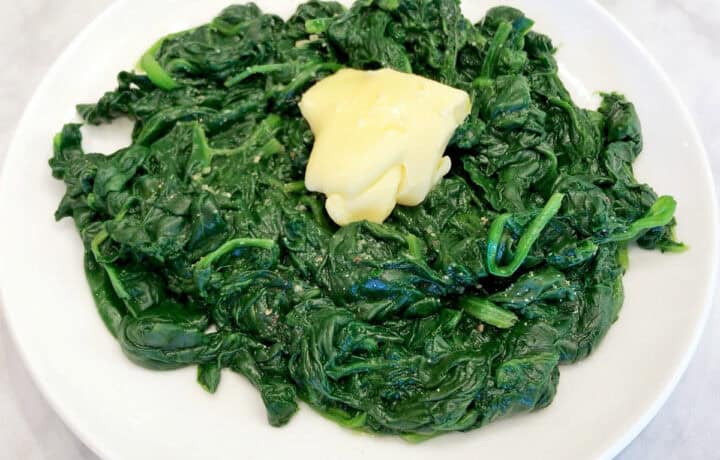 The spinach is served, topped with butter.