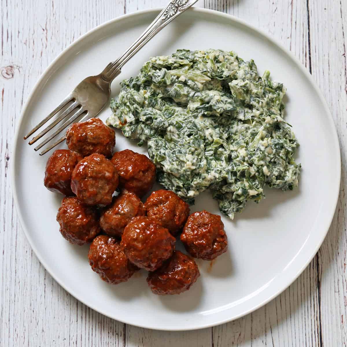 Cocktail meatballs are served with creamed spinach.