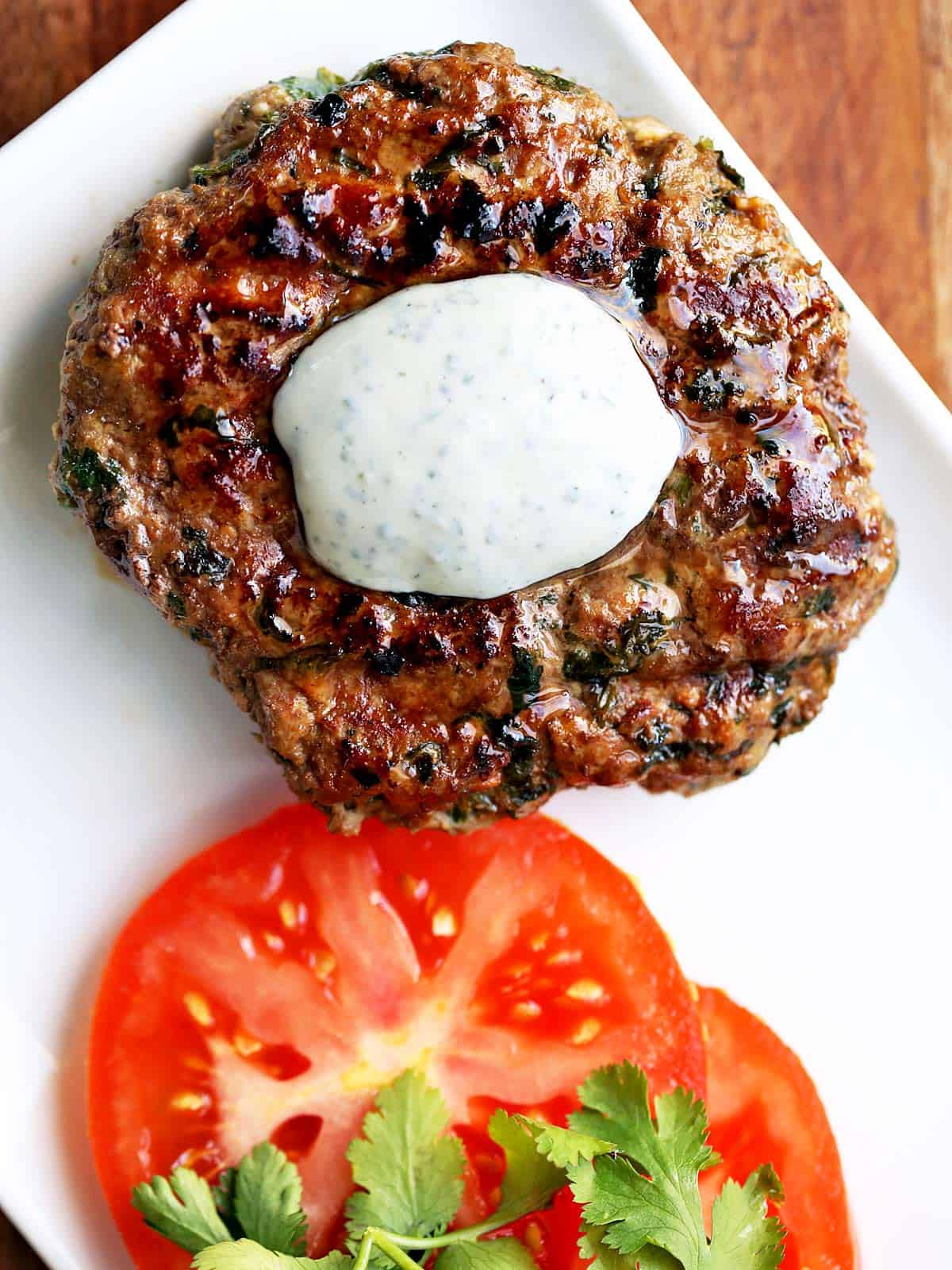 A lamb burger is topped with a yogurt sauce.