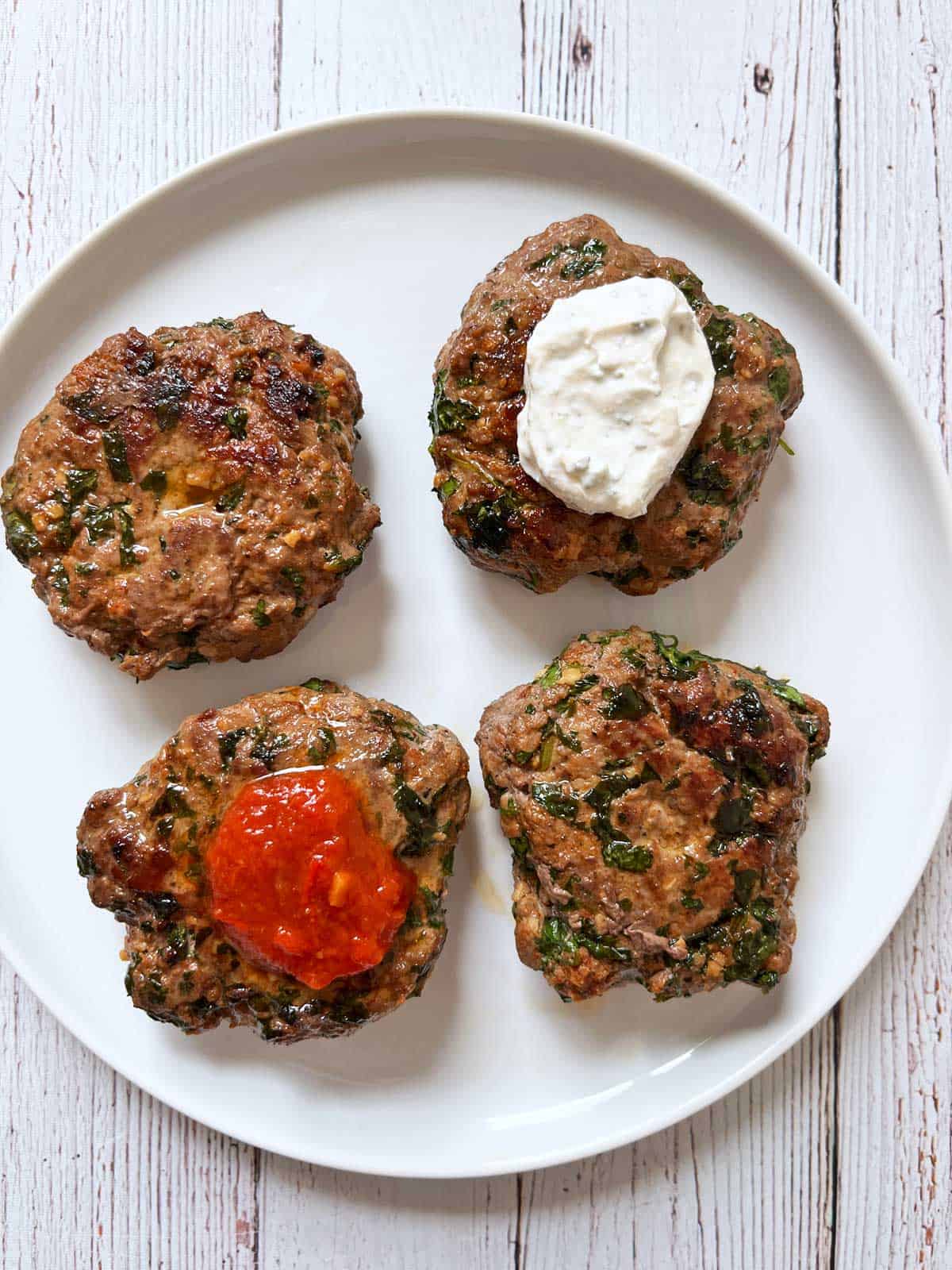 Lamb burgers are topped with a yogurt sauce and with harissa.