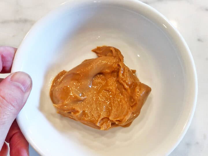 A white bowl with peanut butter.