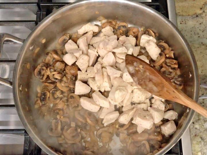 Adding the cooked chicken back to the skillet.