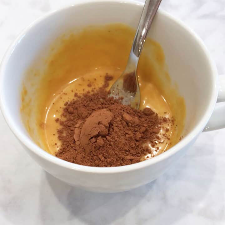 Adding cocoa powder to the mug cake.