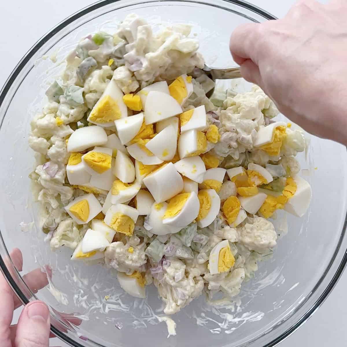 Adding eggs to the salad.