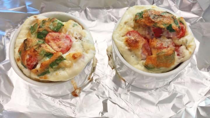 Two egg white muffins are fully baked in a pan.