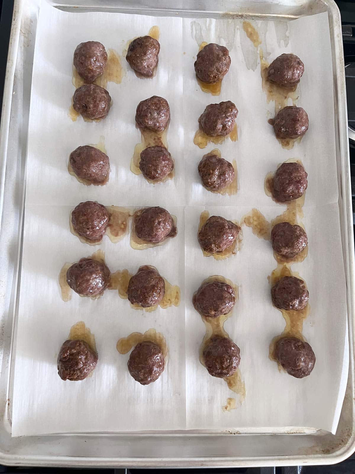 The baked meatballs are on the baking sheet.