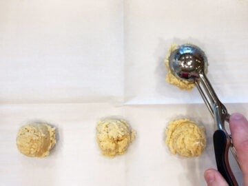 Adding the dough mounds to the baking sheet.