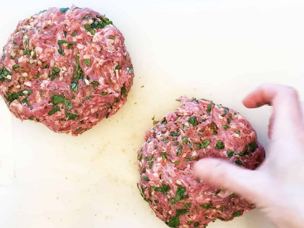 Making a dimple in the center of a burger before cooking.