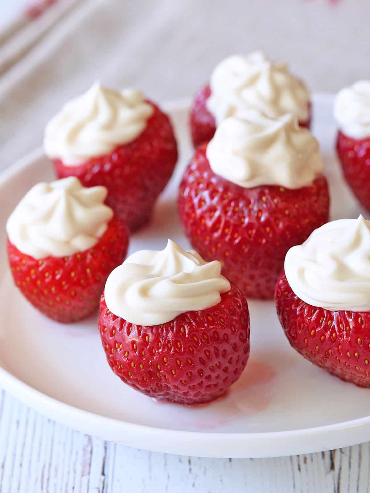 Cheesecake-stuffed strawberries are served on a white plate.