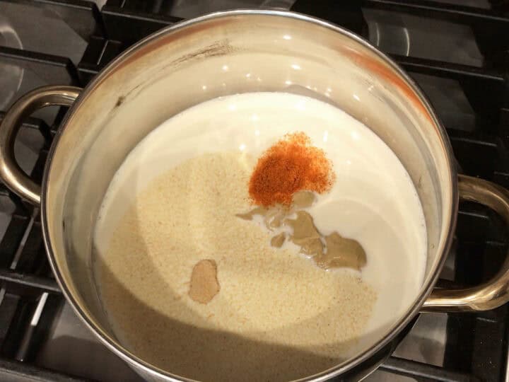 Heating heavy cream, Dijon, and spices in a saucepan.