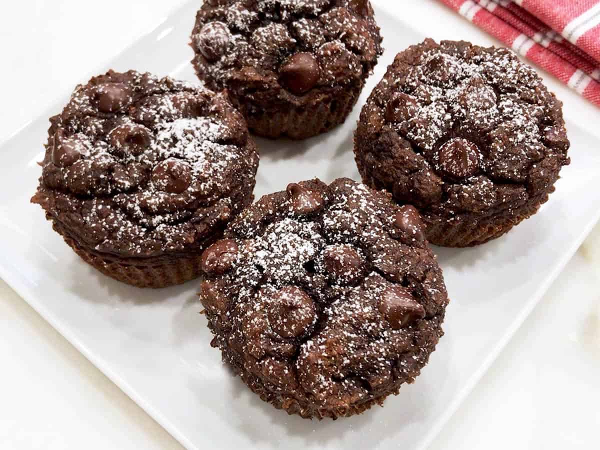 Four keto chocolate muffins are served on a white plate.