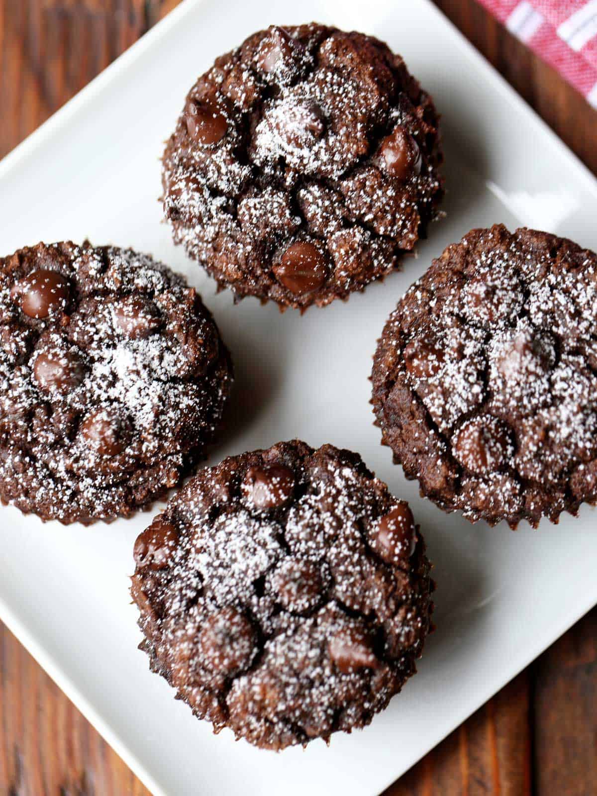 Four keto chocolate muffins are served on a white plate.