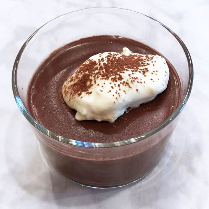 Keto pudding is served in a dessert glass, topped with whipped cream.