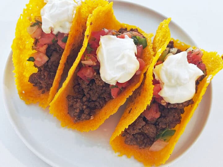 Three keto tacos are served on a white plate.