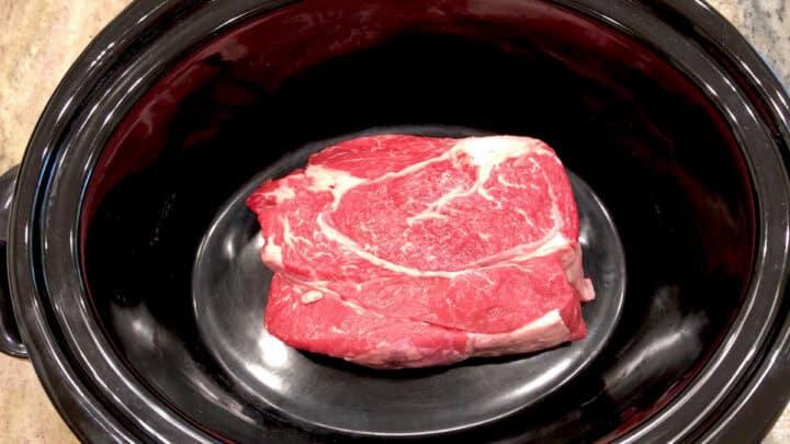 A chuck roast in a slow cooker pan.