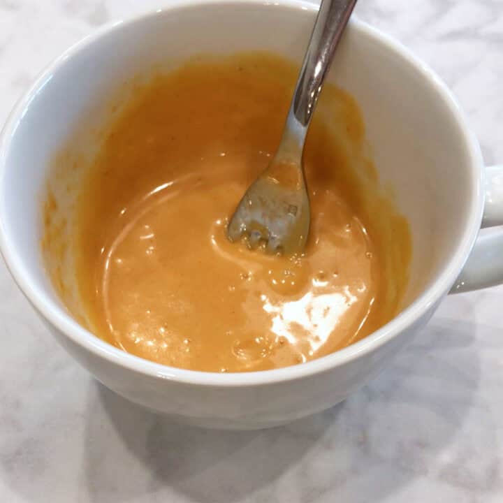 Mixing a nut butter and an egg in a mug.
