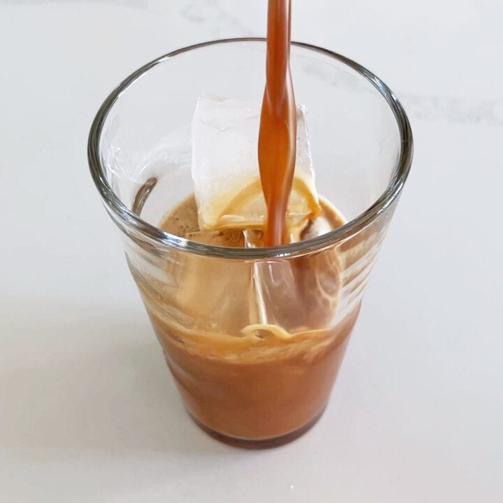 Pouring coffee into an ice-filled glass.