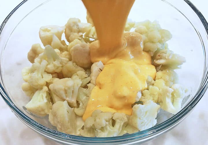 Pouring the cheese sauce on the cauliflower.