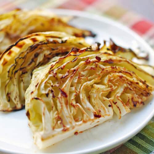 Roasted cabbage is served on a white plate.