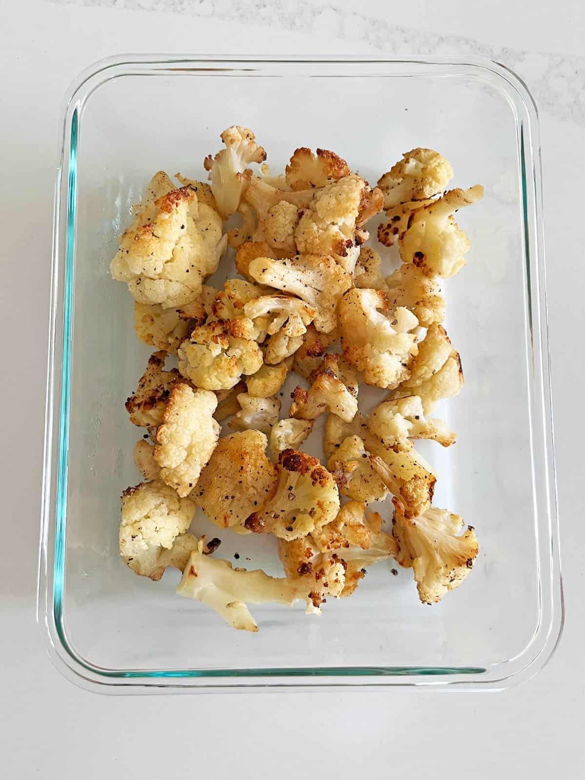 Roasted frozen cauliflower leftovers in a glass container.